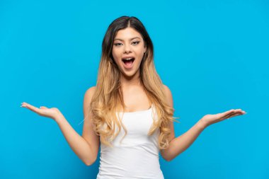 Genç Rus kız mavi arka planda izole edilmiş ve şok olmuş bir yüz ifadesi var.