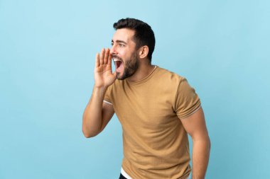 Arka planda sakallı yakışıklı genç bir adam ağzı açık bağırıyor.