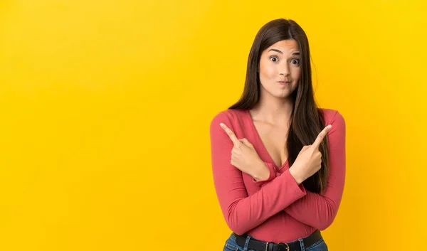 Adolescente Menina Brasileira Sobre Fundo Amarelo Isolado Apontando Para Laterais — Fotografia de Stock