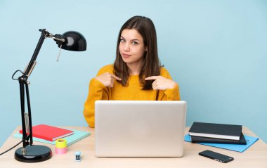 Öğrenci kız, mavi arka planda izole bir şekilde evinde ders çalışıyor.