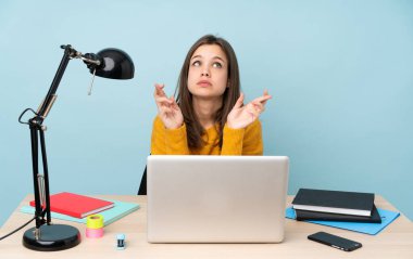 Öğrenci kız, mavi arka planda izole bir şekilde evinde ders çalışıyor.