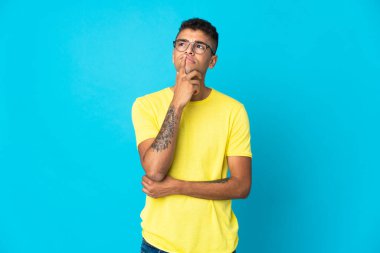 Genç Brezilyalı bir adam mavi arka planda izole edilmiş.