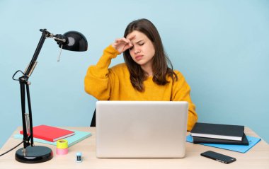 Evinde okuyan öğrenci kız yorgun ve hasta bir ifadeyle mavi arka planda izole edilmiş.