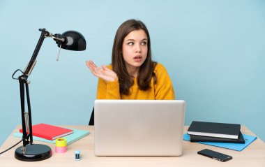 Öğrenci kız evinde mavi arka planda izole bir şekilde ders çalışıyor.