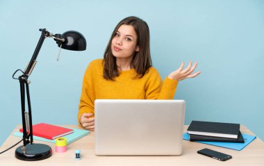 Evinde okuyan öğrenci kız mavi arka planda tek başına gülümsüyor.