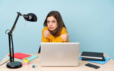 Öğrenci kız evinde çalışıyor. Mavi arka planda izole edilmiş. Donuyor.