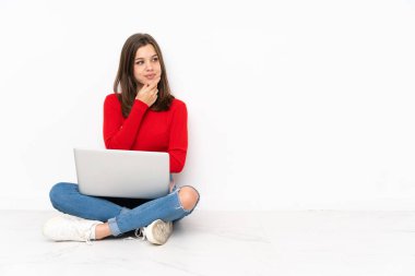 Bilgisayarla çalışan tenaager kız beyaz arkaplanda izole edilmiş olarak yan tarafa bakıyor