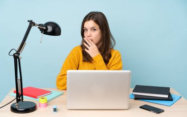 Öğrenci kız evinde çalışıyor. Mavi arka planda tek başına. Şok olmuş ve şaşırmış.