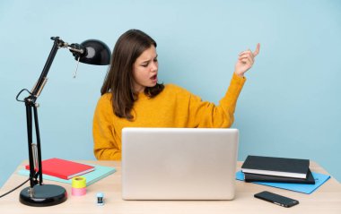 Öğrenci kız evinde çalışıyor. Mavi arka planda tek başına. Gitar hareketi yapıyor.