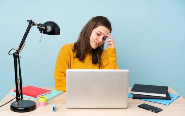 Evinde okuyan öğrenci kız mavi arka planda tek başına gülüyor.