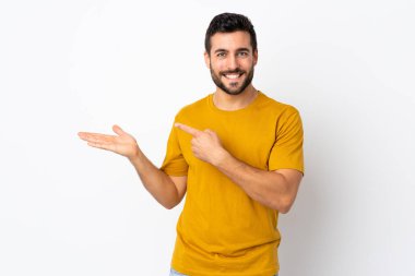 Beyaz arka planda sakallı yakışıklı genç bir adam. Bir ilan vermek için avucunda hayali bir şey tutuyor.