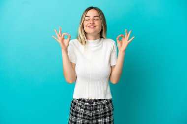 Zen pozunda soyutlanmış mavi arka planı olan genç bir kadın.