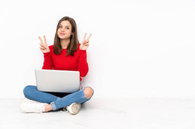 Polisle çalışan hassas kız beyaz arka planda iki elle zafer işareti gösteriyor.