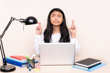 İşyerindeki Asyalı öğrenci bilgisayarla bej arka planda izole edilmiş, şans diliyor ve en iyisini diliyor.