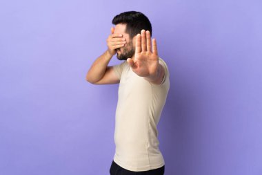 Sakallı ve sakallı genç yakışıklı adam jesti durdurup yüzünü kapatıyor.