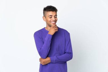 Genç Brezilyalı bir adam beyaz arka planda izole edilmiş, yana bakıyor ve gülümsüyor.