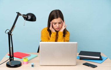 Öğrenci kız evinde çalışıyor. Mavi arka planda, baş ağrısıyla izole edilmiş.