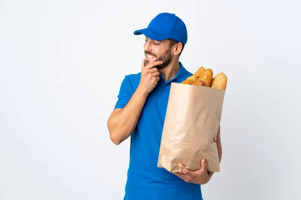 Liefermann Hält Eine Tüte Voller Brote Auf Weißem Hintergrund Isoliert — Stockfoto