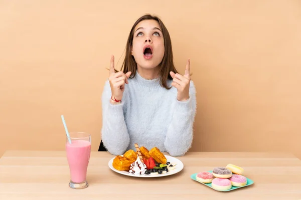 Adolescente Chica Comer Gofres Aislado Beige Fondo Sorprendido Apuntando Hacia —  Fotos de Stock