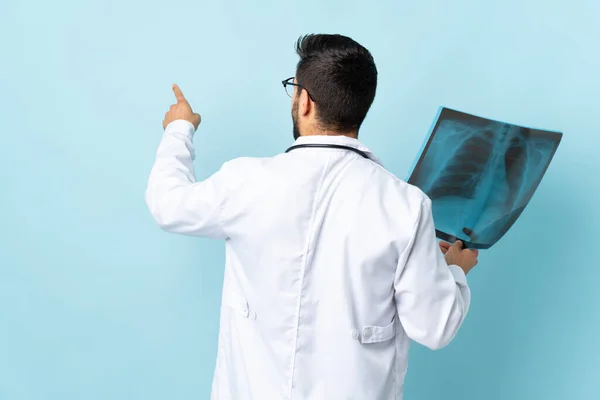 Επαγγελματική Τραυματολόγος Κρατώντας Ακτινογραφία Απομονώνονται Μπλε Φόντο Δείχνει Πίσω Δείκτη — Φωτογραφία Αρχείου