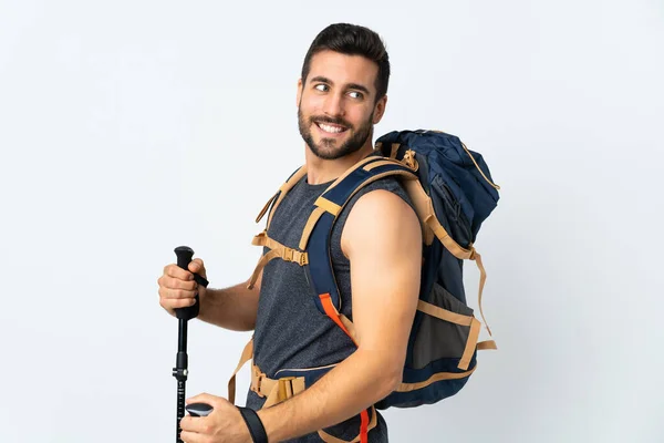 年轻的登山者 背着一个大背包 用白色的背景笑隔离着远足的柱子 — 图库照片
