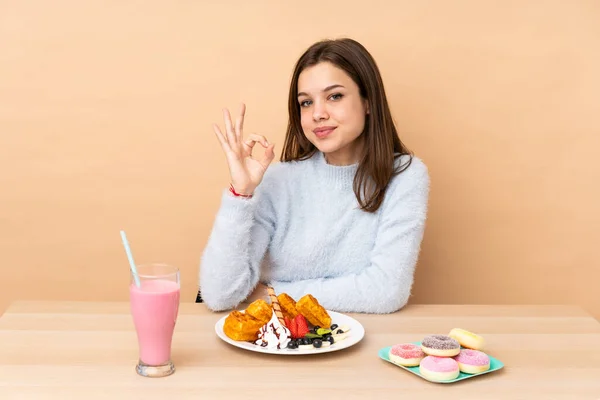 Chica Adolescente Comiendo Gofres Aislados Sobre Fondo Beige Mostrando Signo — Foto de Stock