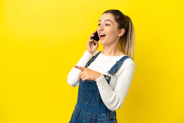 Young Woman Using Mobile Phone Isolated Yellow Background Pointing Finger — Stock Photo, Image