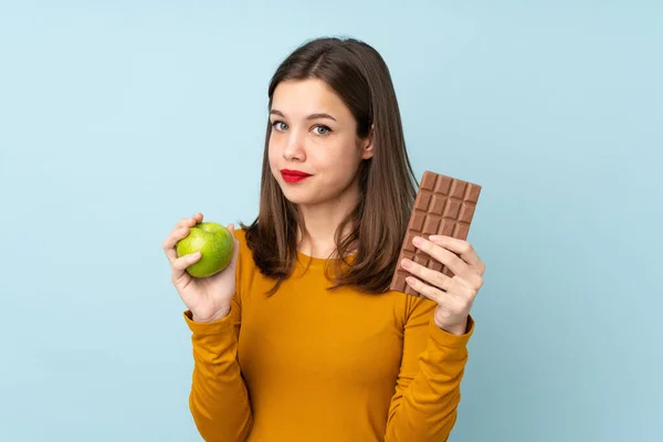 Teenager Girl Isolated Blue Background Taking Chocolate Tablet One Hand — Stock Photo, Image