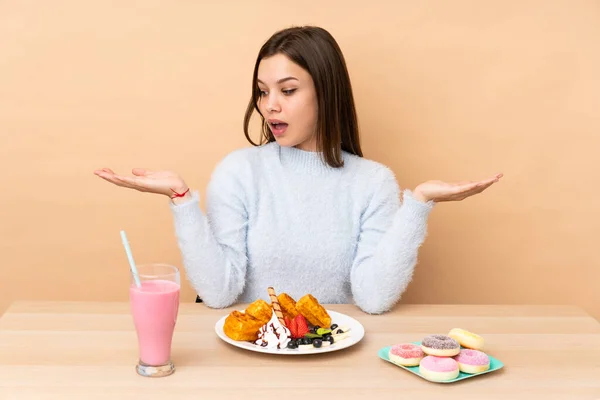 Chica Adolescente Comiendo Gofres Aislados Sobre Fondo Beige Sosteniendo Copyspace —  Fotos de Stock