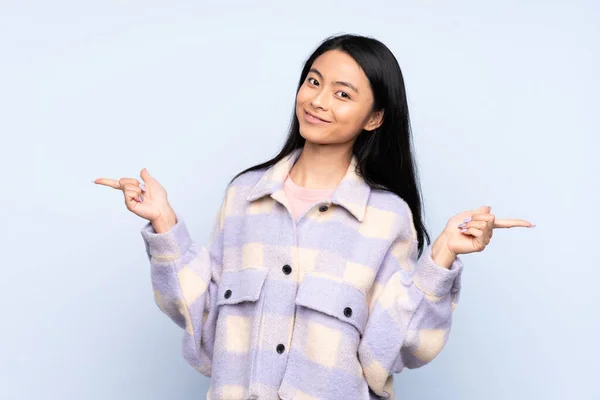 十代の中国の女性は ラテン語と幸せな指を指して青色の背景に隔離 — ストック写真