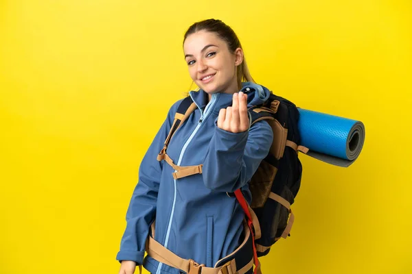 若いです登山女性とともに大きなバックパック上の隔離された黄色の背景作るお金ジェスチャー — ストック写真