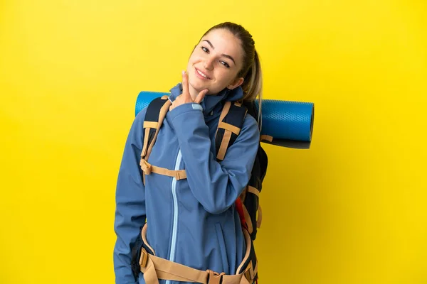 若いです登山女性で大きなバックパックで隔離された黄色の背景幸せと笑顔 — ストック写真