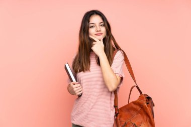 Üniversiteye giden genç bir bayan izole pembe arka planda gülüyor.