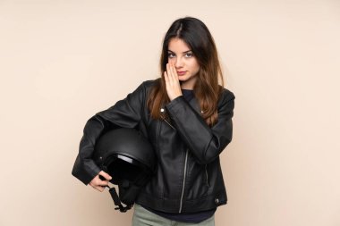 Motosiklet kasklı kadın bej arka planda izole edilmiş bir şekilde bir şeyler fısıldıyor.