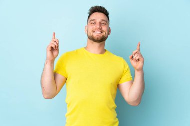 Mavi arka planda izole edilmiş Rus yakışıklı adam harika bir fikre işaret ediyor.