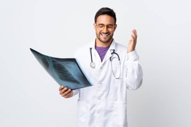 Genç doktor elinde beyaz arka planda izole edilmiş bir radyografi tutuyor.