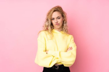 Pembe arka planda izole edilmiş sweatshirt giyen genç sarışın kadın üzgün hissediyor.