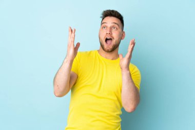 Mavi arka planda yalıtılmış yüzü şaşırmış Rus yakışıklı bir adam.