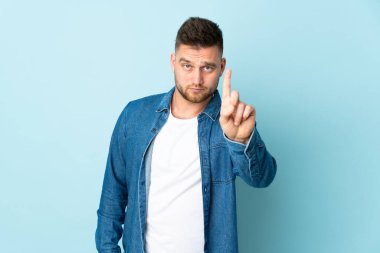 Mavi arka planda izole edilmiş Rus yakışıklı adam ciddi bir ifadeyle birini sayıyor.