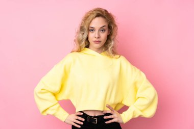 Pembe arka planda izole edilmiş sweatshirt giyen genç sarışın kadın kızgın.