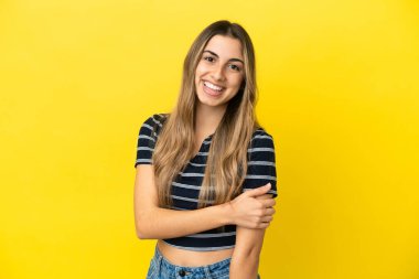 Sarı arka planda izole edilmiş genç beyaz kadın gülüyor.