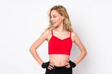 Beyaz arka planda izole edilmiş genç sarışın kadın kolları kalçasında ve yana bakıyor.