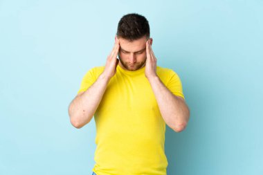 Rus yakışıklı adam mavi arka planda yalnız ve başı ağrıyor.