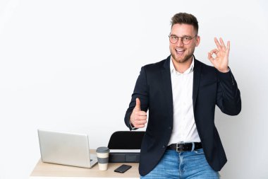 Beyaz arka planda izole edilmiş bir ofiste Rus bir adam tamam işareti ve baş parmak işareti gösteriyor.