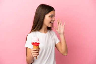 Kornet dondurması ile izole edilmiş pembe arka planda ağzı açık bağıran küçük bir kız.