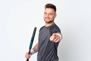 Beyaz arka planda izole edilmiş, tenis oynayan ve ön tarafı işaret eden Rus yakışıklı adam.