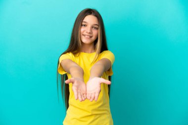 İzole edilmiş mavi arka plan üzerinde küçük bir kız bir reklam koymak için avucunun içinde hayali bir alan tutuyor.