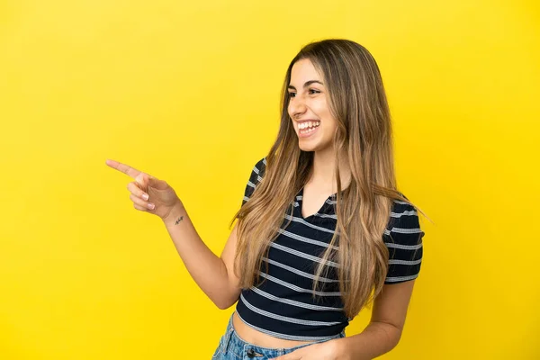 年轻的高加索女人在黄色背景下被隔离 手指指向侧面并展示了一种产品 — 图库照片