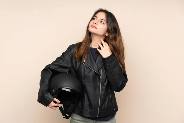 ベージュの背景に隔離されたオートバイのヘルメットを持つ女性考え方 — ストック写真