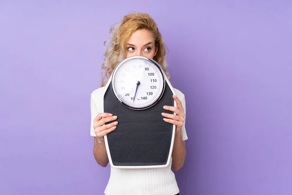 Giovane Donna Bionda Isolata Sfondo Viola Con Pesatrice Nascosta Dietro — Foto Stock